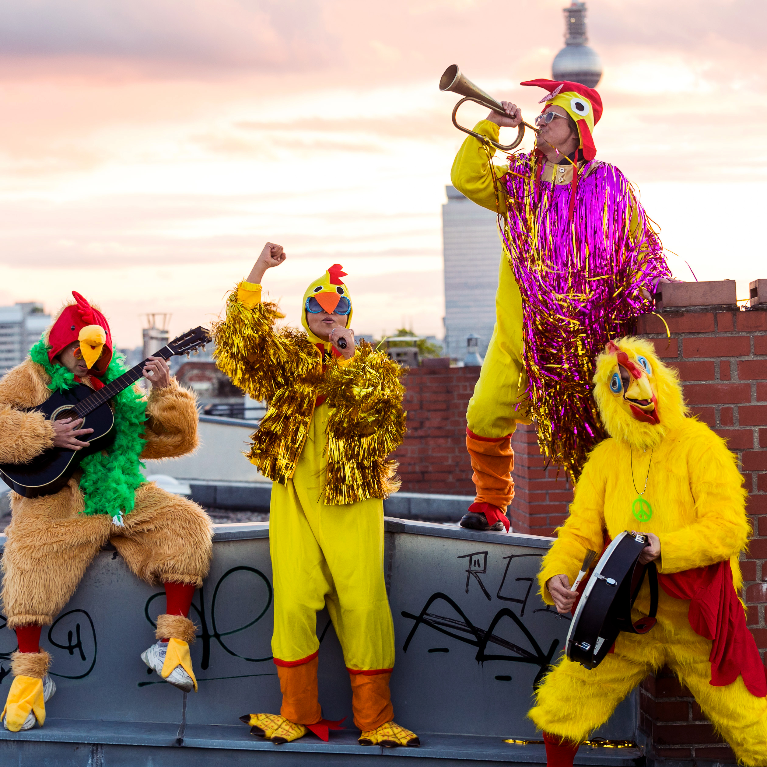 A costumed chicken band playing music on a rooftop at sunset